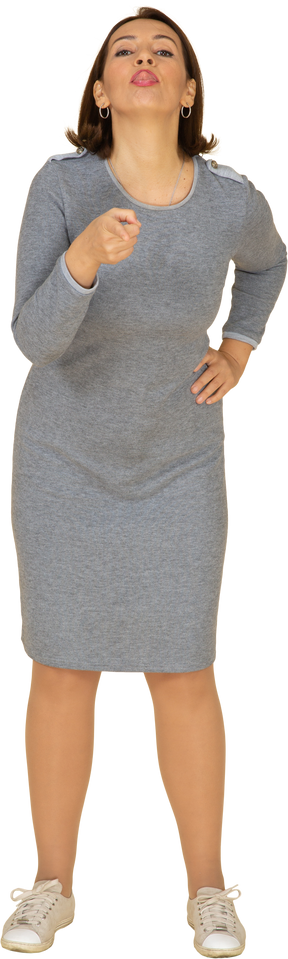 Vista frontal de uma mulher de vestido cinza apontando com um dedo