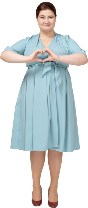 Vista frontal de uma mulher de vestido azul mostrando um gesto de coração