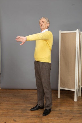 Three-quarter view of a displeased old man outstretching his hand