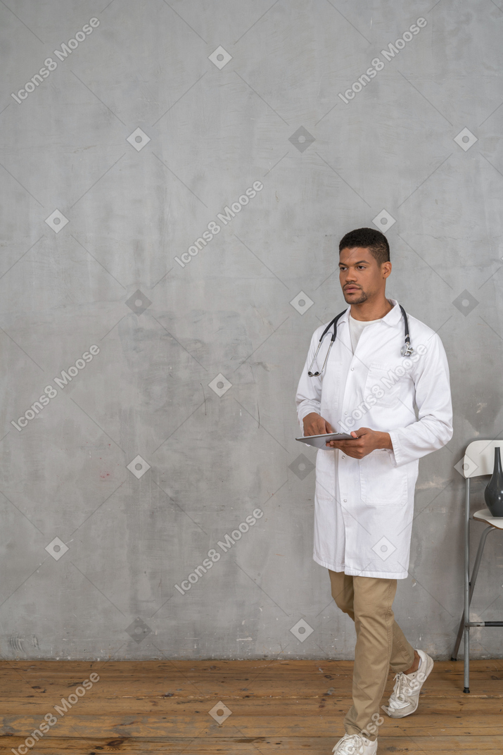 Médico varón con tableta caminando