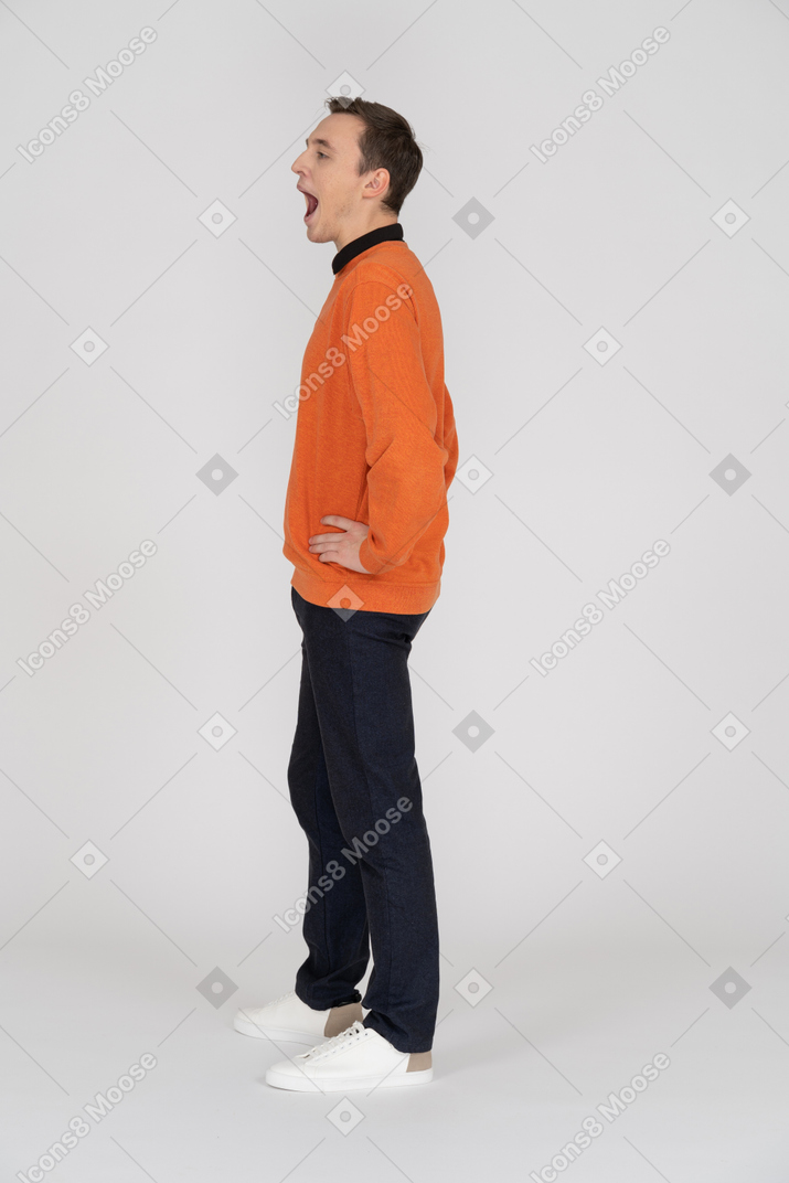 A yawning man in an orange sweater and black pants
