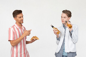 Mann hält ein stück pizza und ein anderer mann hält bier