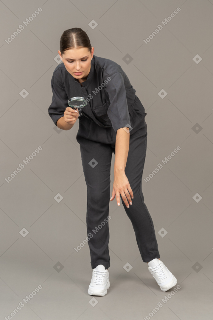 一个穿着连身衣、拿着放大镜的年轻女子的前视图