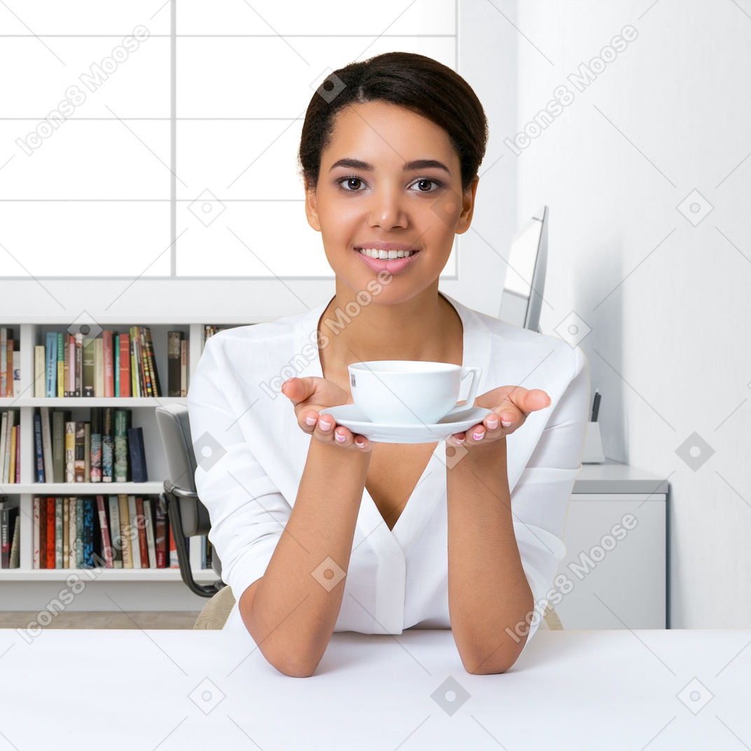 A woman sitting at a table holding a cup of coffee
