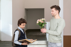 A man giving a flower to a young boy