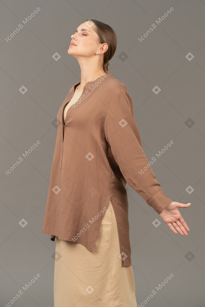 Vista lateral de una mujer joven con los ojos cerrados y los brazos abiertos