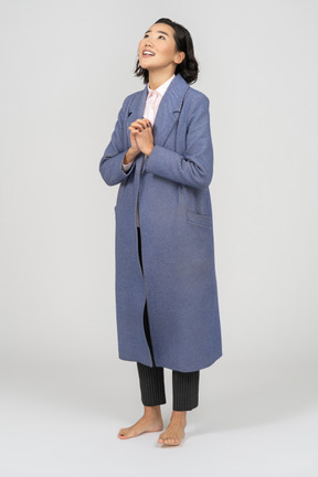 Cheerful woman in coat with folded hands