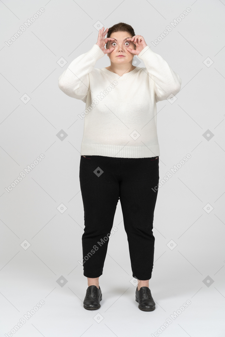 Plump woman in casual clothes looking through imaginary binoculars