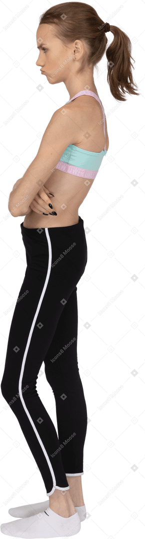 Vista lateral de uma adolescente em roupas esportivas cruzando as mãos e tricotando as sobrancelhas