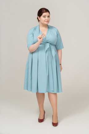 一个穿着蓝色连衣裙的女人的前视图，展示了一件小物件