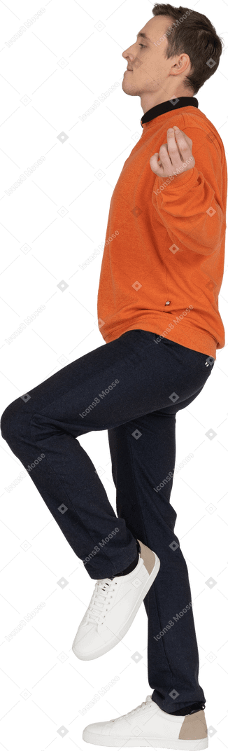 Giovane uomo in felpa arancione in posa