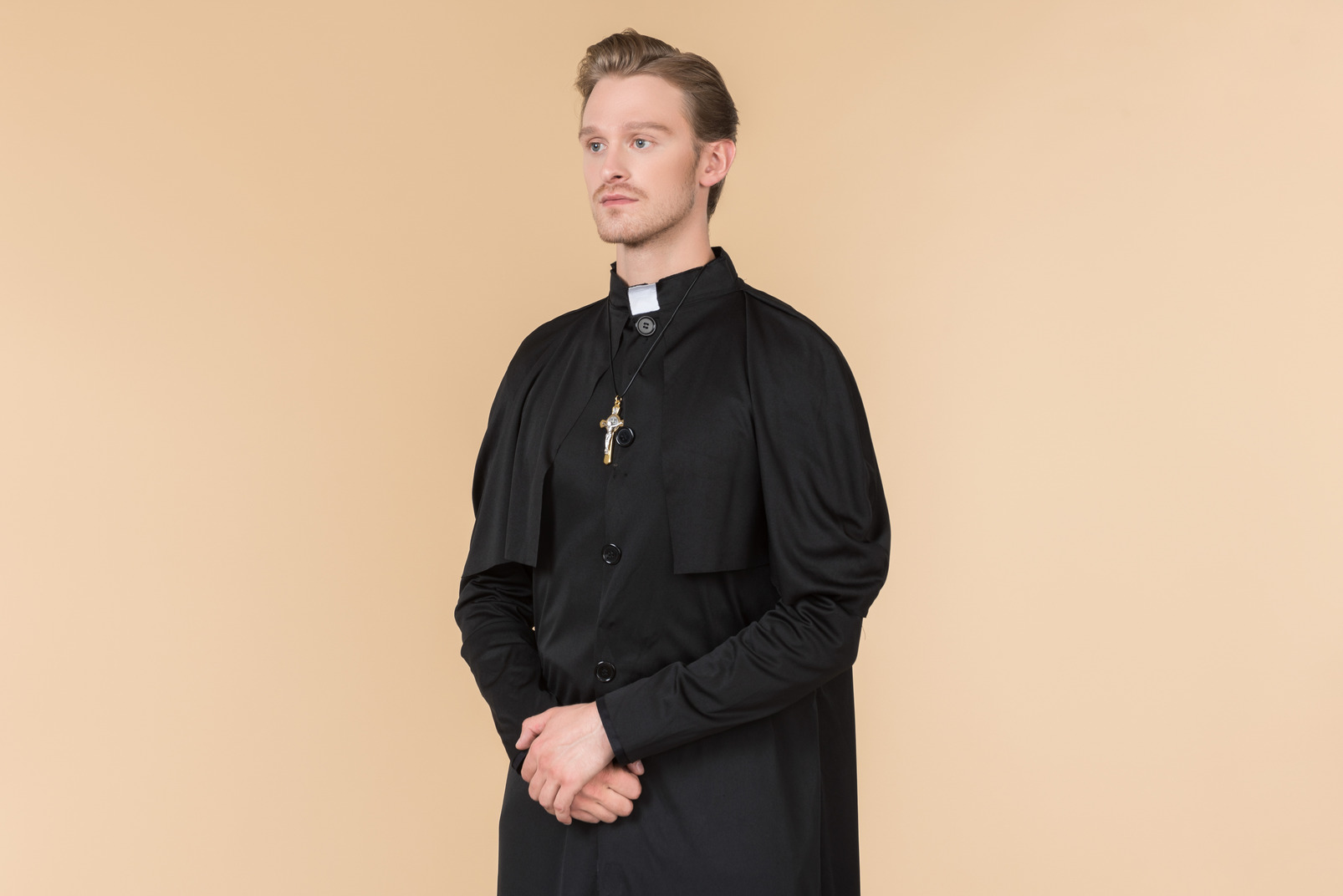 Catholic priest in cassock standing in profile