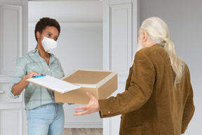 Correio feminino mascarado, entregando uma encomenda