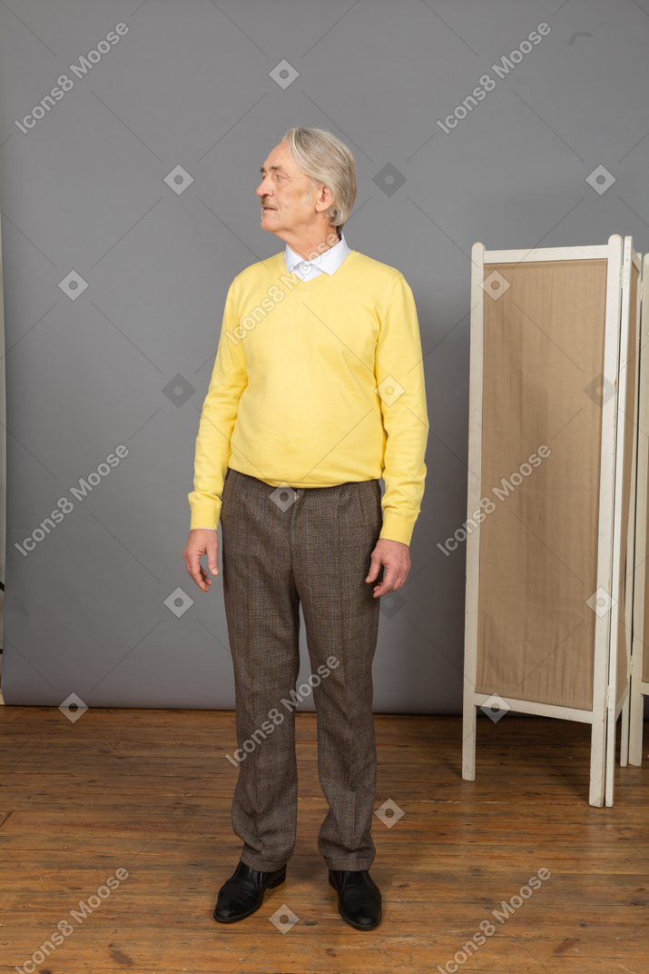 一个老人在黄色的套衫，转动他的头的前视图