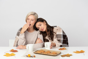 Junge frauen, die morgens kaffee trinken und gähnen