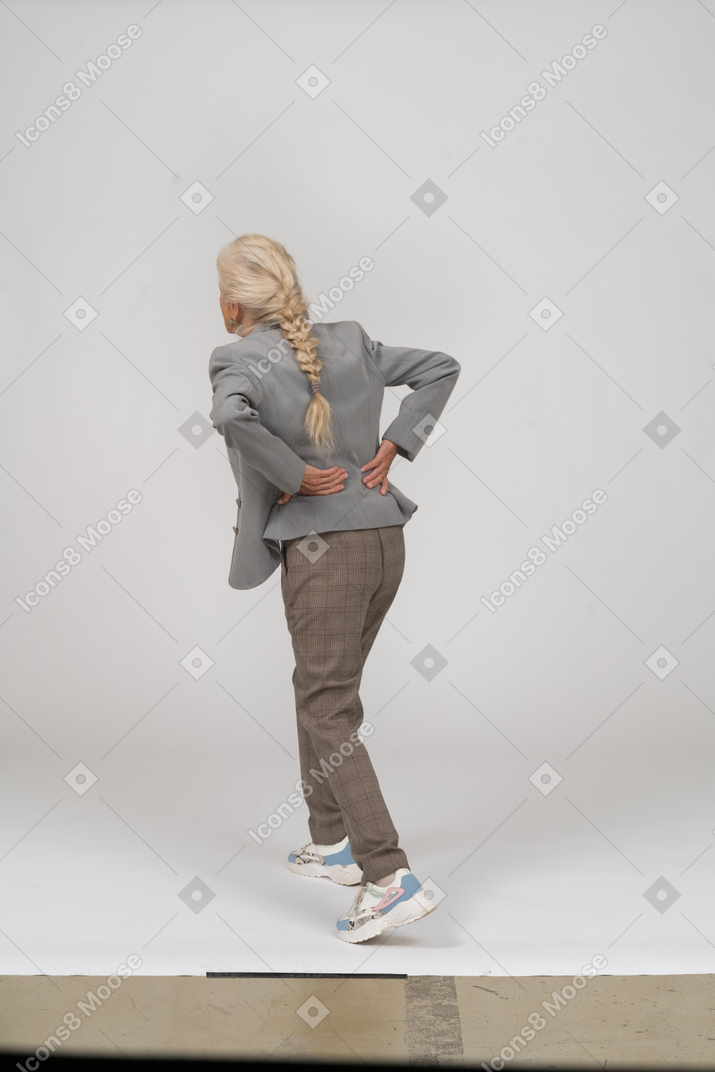 ヨガをしているスーツの老婦人の背面図