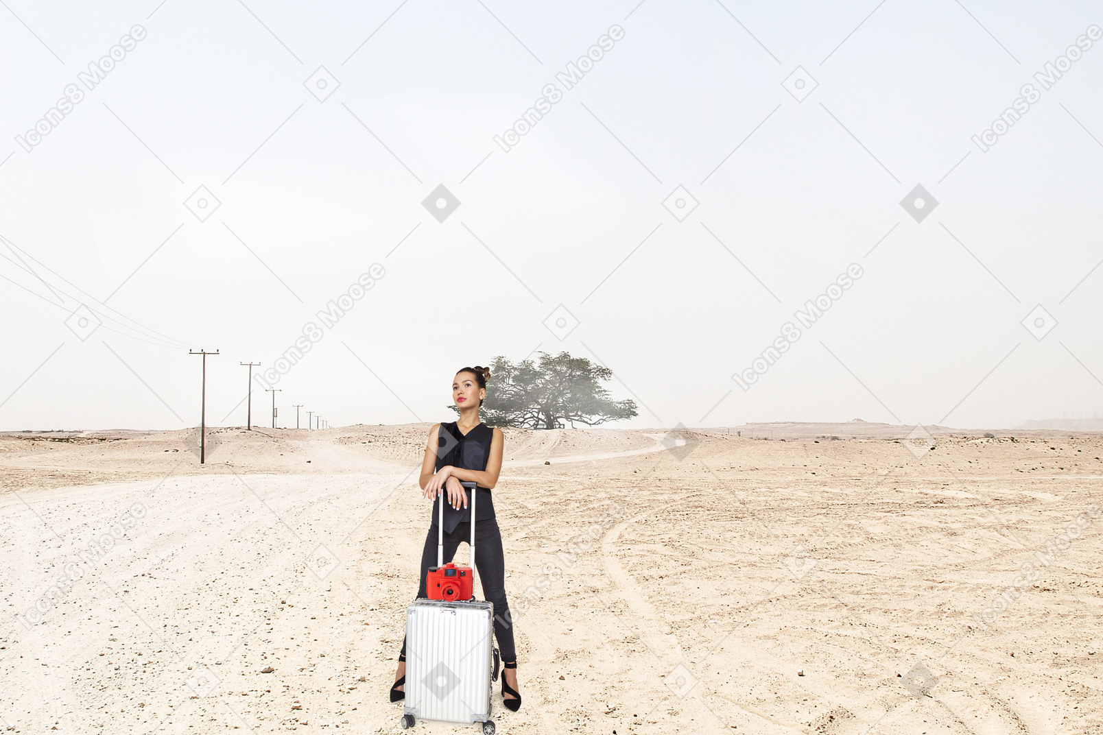 站在沙漠中提着手提箱的女人