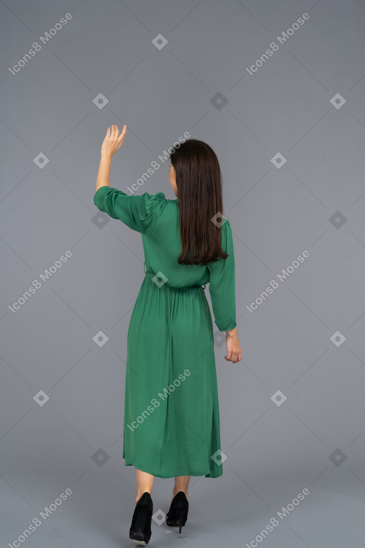 Вид сзади приветствующей молодой леди в зеленом платье