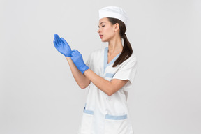 Infirmière attrayante dans une robe médicale mettant des gants en latex