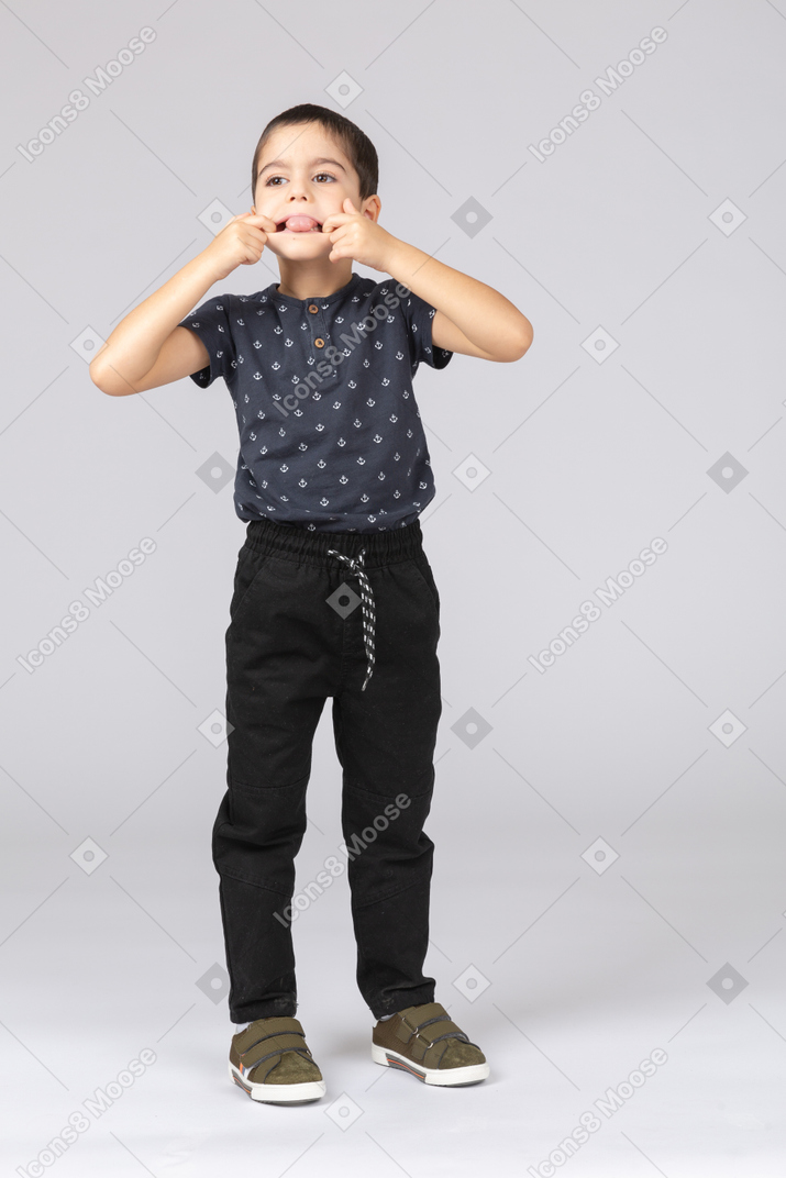 Front view of a cute boy putting fingers in mouth and showing tongue