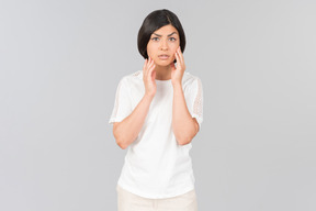 Young indian woman looking attentively at her face