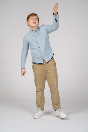 Vista frontal del chico lindo apuntando hacia arriba con una mano