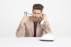 Handsome young man holding phone receiver close to his ear