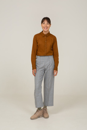 Front view of a smiling young asian female in breeches and blouse standing still