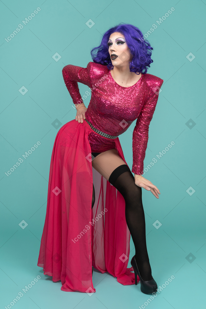 Portrait of a drag queen in pink dress posing with arched back and hand resting on knee