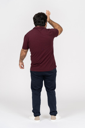 Rear view of a man holding hand to his head