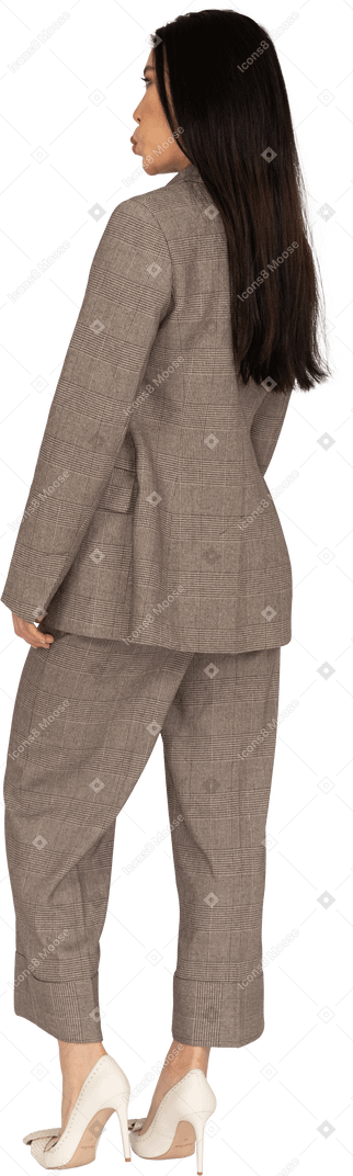 Three-quarter back view of a pouting young lady in brown business suit