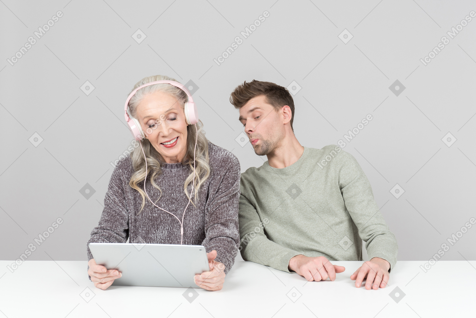 Mulher velha em fones de ouvido e cara jovem assistindo algo em um tablet digital