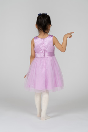 Back view of a little girl in a tutu dress pointing right