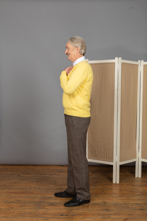 Side view of an smiling old man near the screen crossing hands