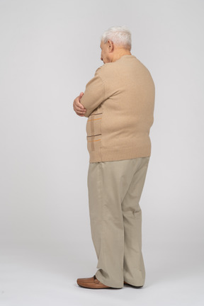 腕を組んで立っているカジュアルな服装の老人の側面図