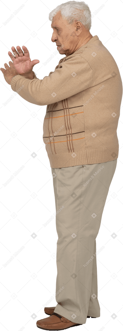 Vista lateral de un anciano con ropa informal que muestra un gesto de parada