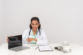 Confiante médico feminino mostrando algo em seu laptop
