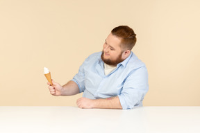 Big man sitting at the table and holding ice cream