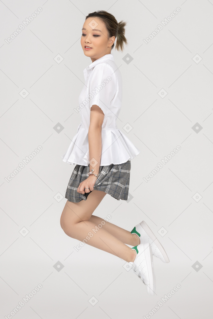 Cheerful asian girl jumping sideways to camera
