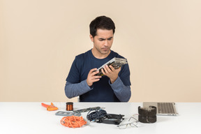 A young man in casual blue clothes working with computer details