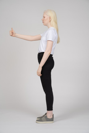 Side view of a young girl standing with thumbs up