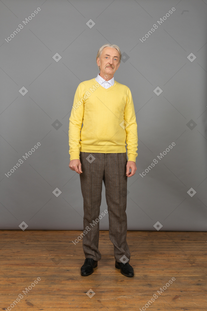 Vorderansicht eines alten mannes, der gelben pullover trägt und still steht