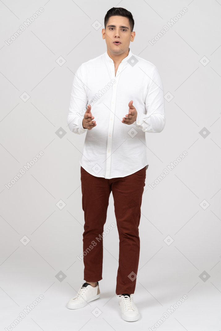 Front view of a young latino man looking at camera as if explaining something