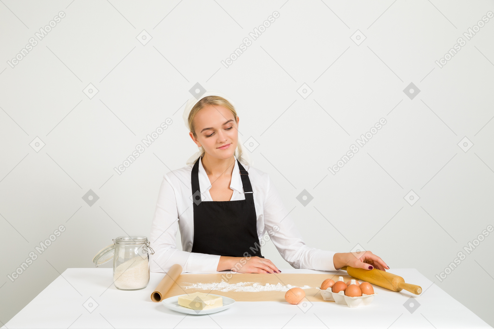 Female chef sitting at the table with pastry ingredients on it