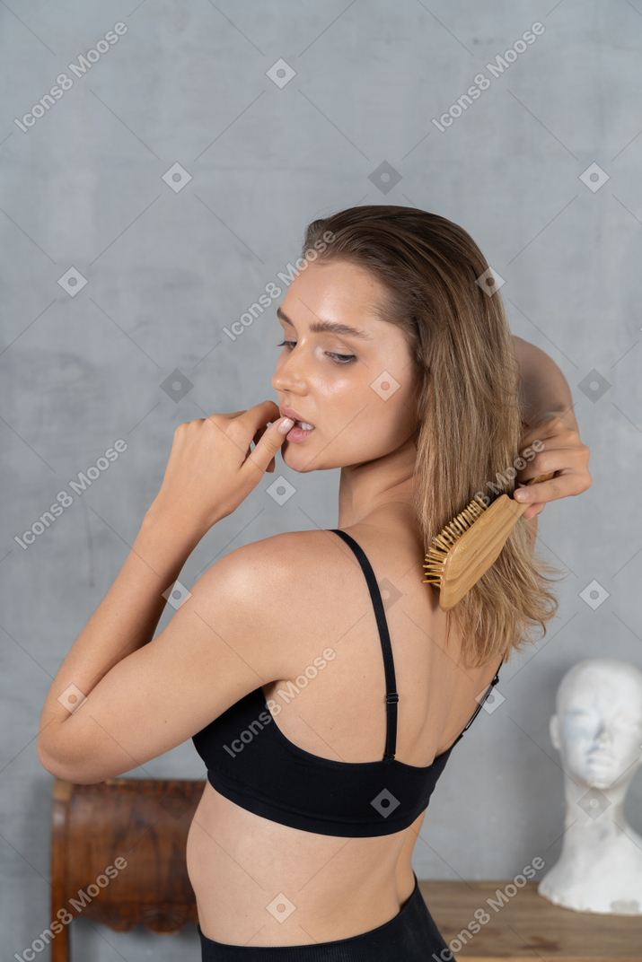 Portrait of a young woman brushing her hair & touching her lip
