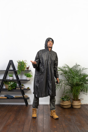 Mann im regenmantel prüft, ob es regnet