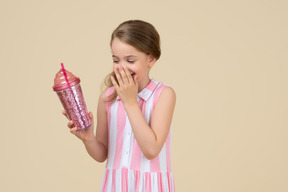 Cute little girl holding a plastic cup with a straw