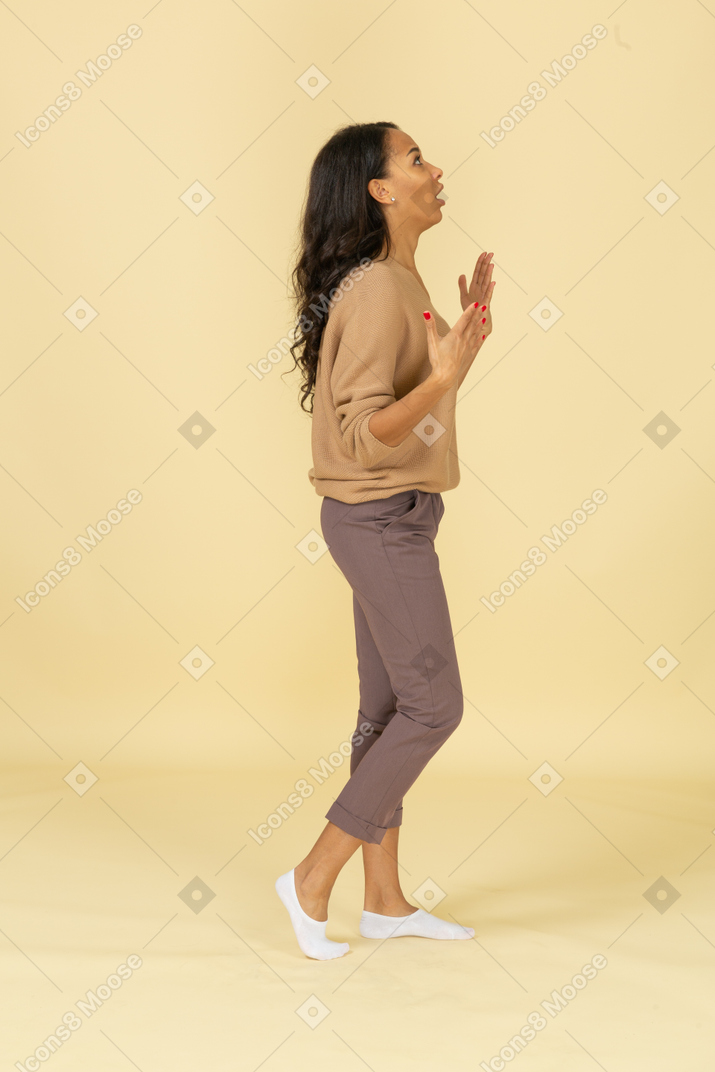 Vista lateral de uma jovem fêmea de pele escura com respiração pesada acenando com as mãos