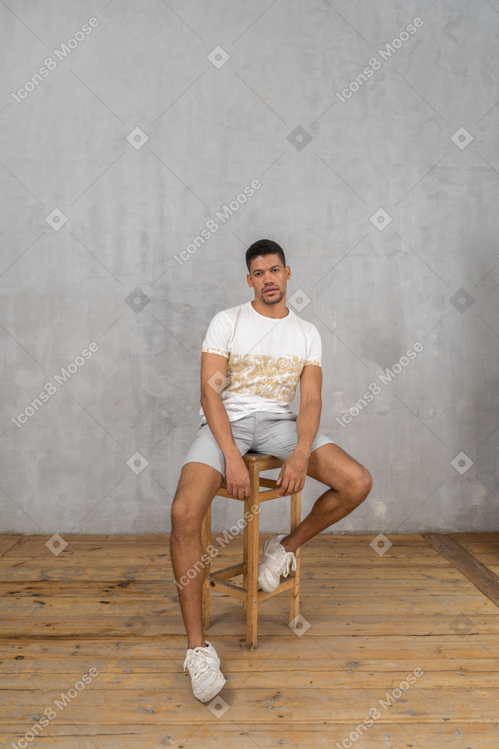 Relaxed young man sitting with hands in front