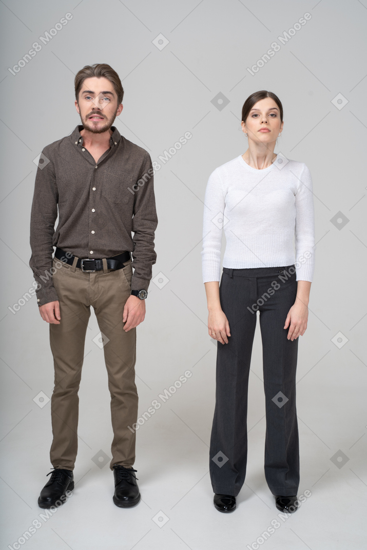 一对年轻夫妇在抬头的办公室服装的前视图